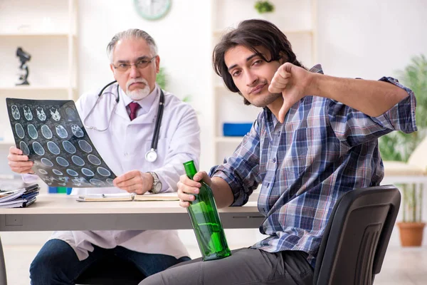 Young male alcoholic visiting old doctor — Stock Photo, Image