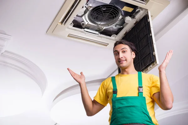 Ung reparatör reparera tak luftkonditionering enhet — Stockfoto
