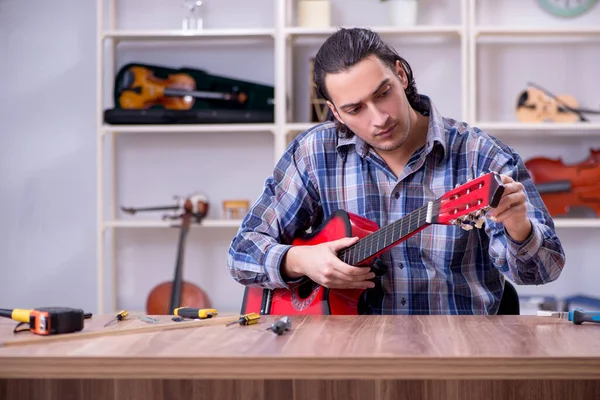 Junger gutaussehender Reparateur repariert Gitarre — Stockfoto