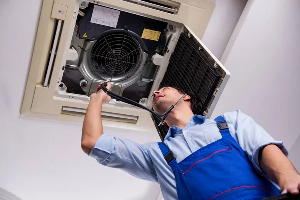 Jonge reparateur repareert airconditioning aan het plafond — Stockfoto