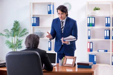 Patron ve erkek asistanı ofiste çalışıyor.