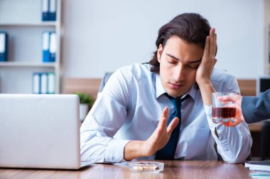 İş yerinde alkol ve sigara içen bir erkek işçi.