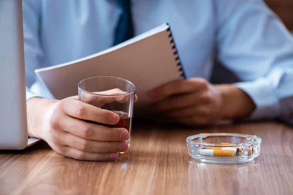 Male employee drinking alcohol and smoking cigarettes at workpla — Stock Photo, Image