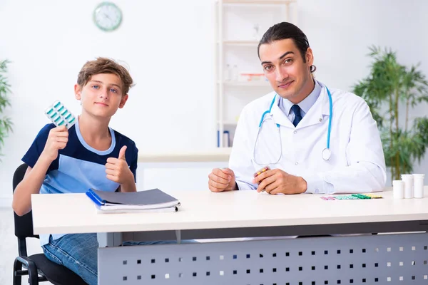 Giovane medico maschio esaminando ragazzo in clinica — Foto Stock