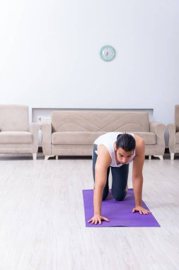 Genç adam evde antrenman ve egzersiz yapıyor.