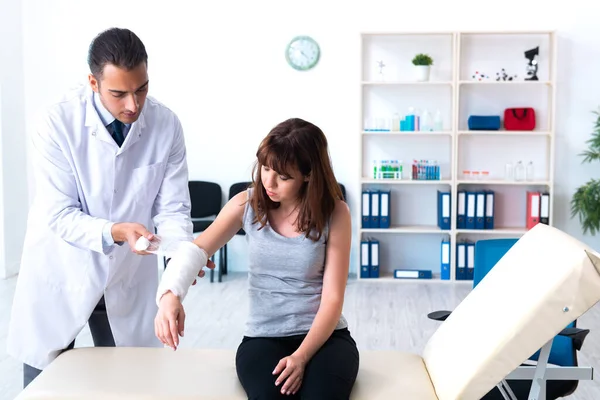 Jonge vrouw op bezoek bij mannelijke arts traumatoloog — Stockfoto