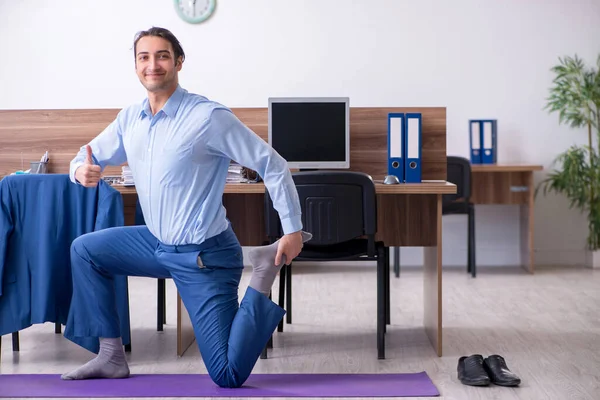 Jonge knappe zakenman doet oefeningen op het werk — Stockfoto