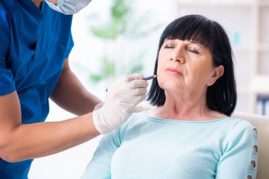 Yaşlı kadın estetik ameliyat için erkek doktoru ziyaret ediyor.