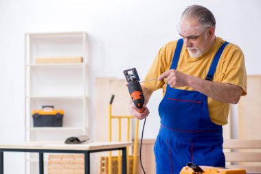 Yaşlı erkek marangoz atölyede çalışıyor.