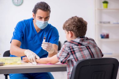 Genç çocuk hastanede doktoru ziyaret ediyor.