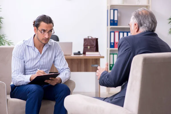 Oude man op bezoek bij jonge mannelijke dokter psycholoog — Stockfoto