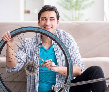 Evde bisiklet tamir eden genç bir adam.