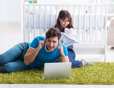 Yeni doğmuş bebekleriyle halıda oturan genç ebeveynler.