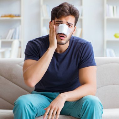 Genç adam estetik cerrahi burnundan sonra evde iyileşiyor.