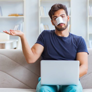 Genç adam estetik cerrahi burnundan sonra evde iyileşiyor.