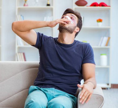 Genç adam estetik cerrahi burnundan sonra evde iyileşiyor.