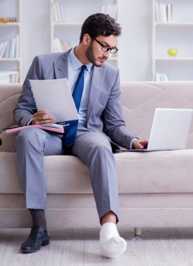 Koltuk değneği ve kırık bacağı olan bir iş adamı.