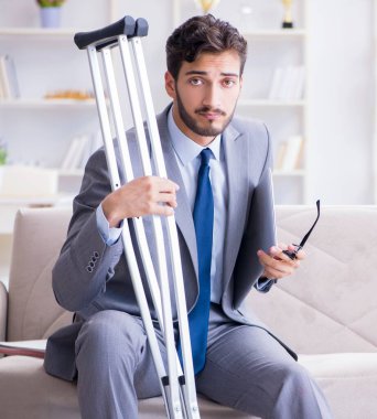 Koltuk değneği ve kırık bacağı olan bir iş adamı.