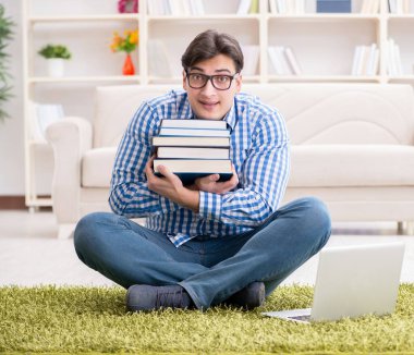 Genç yakışıklı adam evde yerde oturuyor.