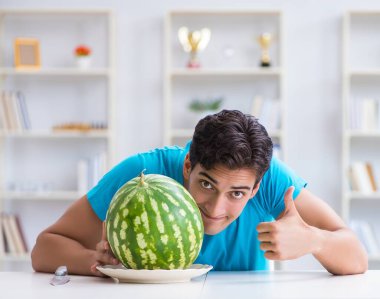 Evde karpuz yiyen bir adam.