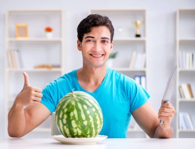 Evde karpuz yiyen bir adam.