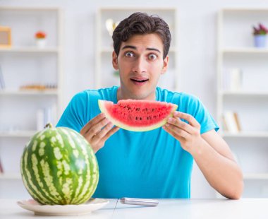 Evde karpuz yiyen bir adam.