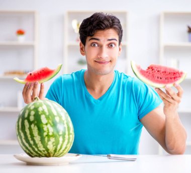 Evde karpuz yiyen bir adam.