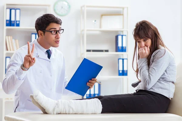 Arzt untersucht Patient mit gebrochenem Bein — Stockfoto