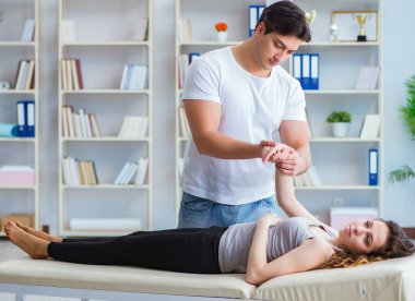 Genç doktor kayropraktik uzmanı kadın hastaya masaj yapıyor.