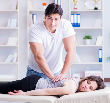 Genç doktor kayropraktik uzmanı kadın hastaya masaj yapıyor.