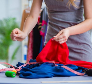 Atölyede çalışan genç bayan terzi yeni elbise üzerinde çalışıyor.