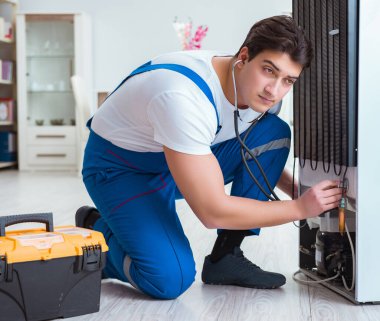 Tamirci müteahhit DIY konseptinde buzdolabını tamir ediyor.