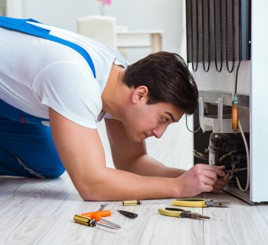 Tamirci müteahhit DIY konseptinde buzdolabını tamir ediyor.