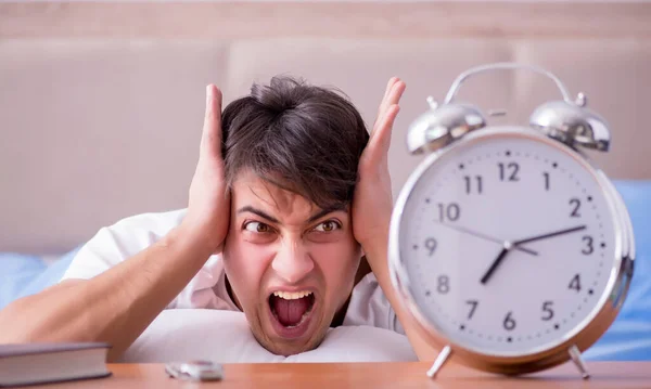Homme au lit frustré souffrant d'insomnie avec un cloc d'alarme — Photo