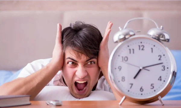 Man in bed frustrated suffering from insomnia with an alarm cloc — Stock Photo, Image