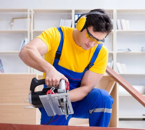 Reparador carpintero cortando aserrar una tabla de madera con un circuito —  Fotos de Stock