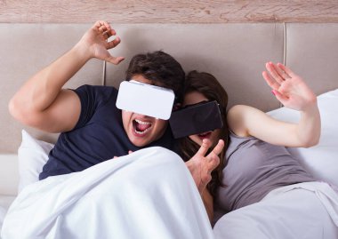 Yatakta sanal gerçeklik gözlüklü eş ve koca.
