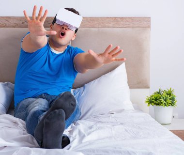 Yatakta sanal gerçeklik başlığı takan genç bir adam.