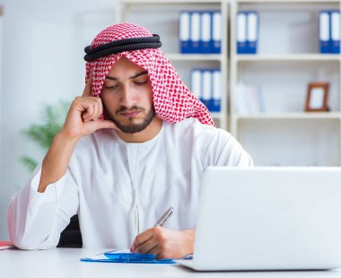 Ofiste çalışan Arap işadamı bir Pi ile evrak işi yapıyor.