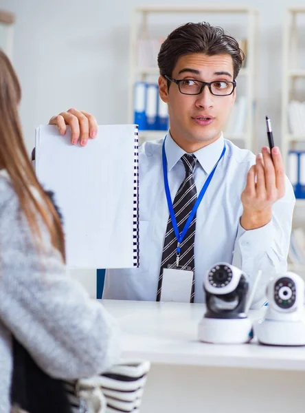 Assistente de vendas mostrando câmeras para o cliente na loja — Fotografia de Stock