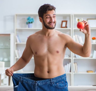 Kilo verme konseptinde büyük beden pantolon giyen bir adam.