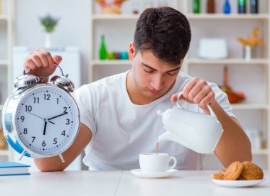 Çalar saati olan bir adam kahvaltıda uyuyakalıyor.