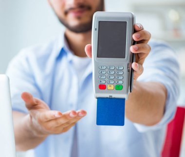 POS terminali ile kredi kartı işlemi yapan adam