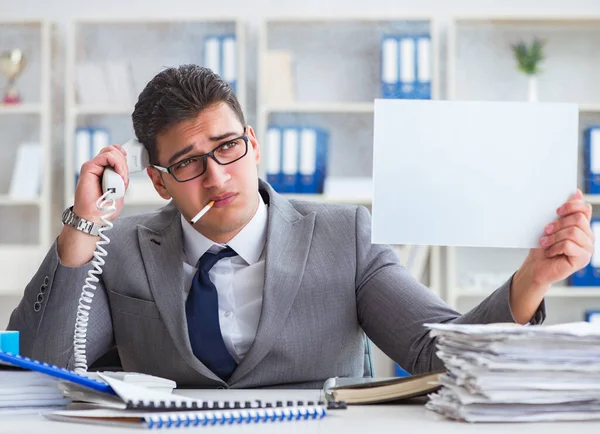 Businessman smoking at work in office holding a blank message bo — Stock Photo, Image