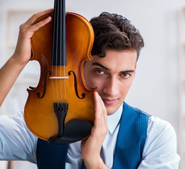 Genç müzisyen evde keman çalıyor.