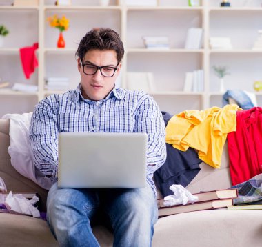 Genç adam dağınık bir odada çalışıyor.