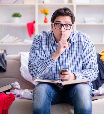 Genç adam dağınık bir odada çalışıyor.