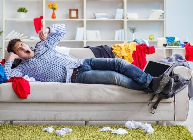 Genç adam dağınık bir odada çalışıyor.