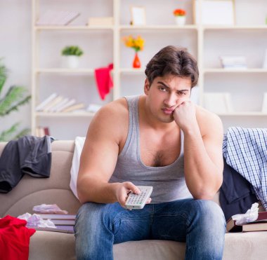 Genç adam dağınık bir odada çalışıyor.