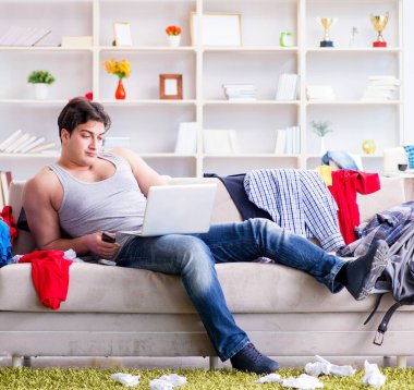 Genç adam dağınık bir odada çalışıyor.